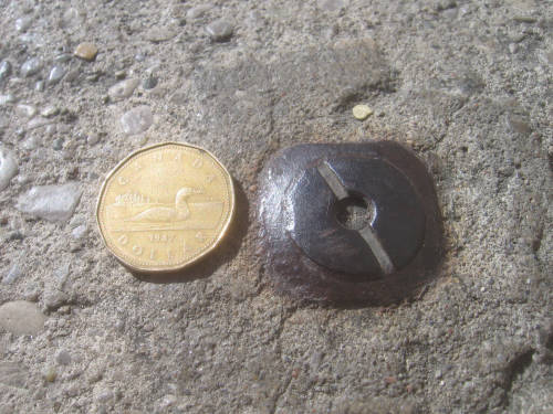 [Slotted pin-like metal thing in the sidewalk]